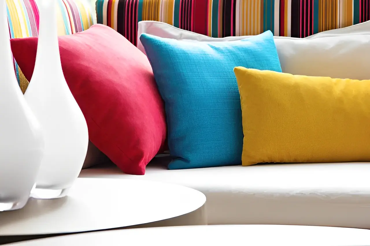 2db23eae-6caa-4d41-8fb9-b3f8b6c6db2d A white couch with colorful pillows on it.