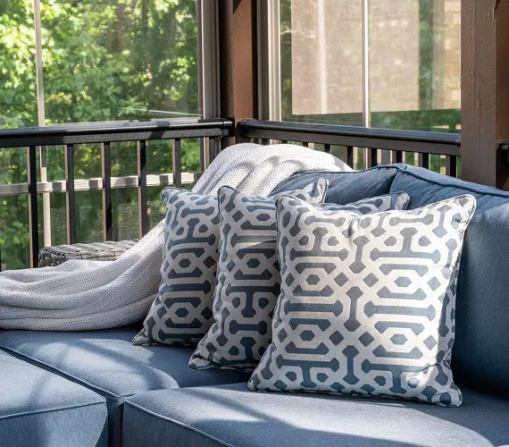Outdoor seating with patterned pillows and blanket.