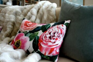 Colleen Dawson of Raye Design created this pink floral lumbar pillow, shown on a sofa with a faux fur throw blanket and slate throw pillow - custom pillows fabricated by Pillows by Dezign, a custom decorative pillow fabricator for hospitality, commercial and residential interior design projects.